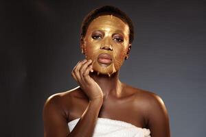 Woman applying gold facial mask in spa setting, emphasizing skincare and beauty routine at evening photo