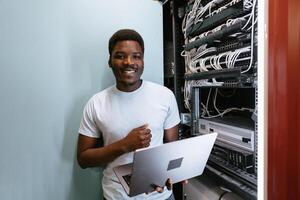 Technician working on network cables in a data center with laptop during daytime photo