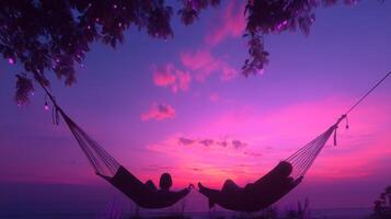 Couples relaxing in hammocks during a vibrant sunset by the beach under glowing lights photo