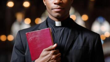 Clergy member holds a scripture book while standing in a dimly lit church during a worship service photo