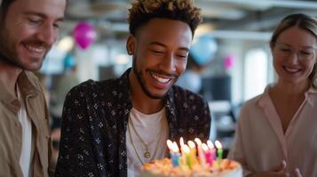Friends celebrate a birthday with a cake and candles in a cheerful office environment during a festive gathering photo