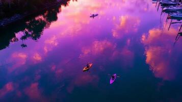 Kayakers enjoy a serene sunset paddle on a tranquil lake with vibrant pink and purple reflections photo