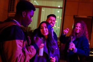 Friends enjoying a lively gathering at night with drinks and music in an urban setting photo