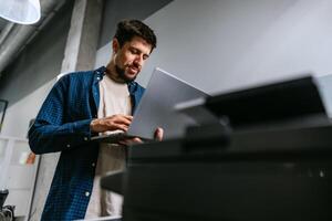 Man working on laptop in modern office space during daylight hours photo