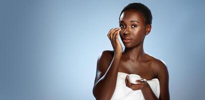 Woman applying skincare product in minimalistic studio setting during daytime routine photo