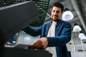 Man efficiently using a printer in a modern office environment during daytime hours photo