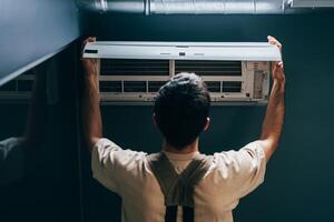 Man installs an air conditioning unit in a modern room during daylight hours photo
