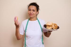 Woman Contrasting Doughnuts and Health Choices With Measuring Tape photo