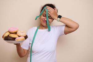 Woman Struggles With Healthy Choices, Holding Donuts and Measuring Tape photo