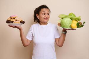 Woman Balancing Plates of Sweet Doughnuts and Healthy Fresh Vegetables in Thoughtful Decision photo