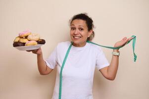 Woman Holding Plate of Sweet Donuts and Tape Measure Expressing Diet Choices photo