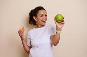 Smiling Woman Holding a Green Apple in One Hand and a Doughnut in the Other, Representing a Healthy vs. Indulgence Choice photo