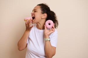 Woman Joyfully Eating Pink Frosted Donuts While Smiling photo
