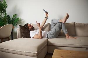 Man Relaxing on Couch Using Smartphone in Cozy Home Interior photo