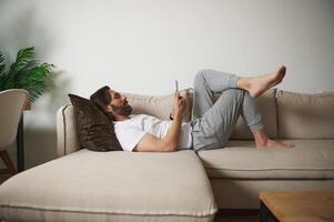 Man Relaxing on a Comfortable Sofa While Using a Smartphone in a Modern Home Setting photo