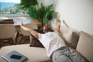 Man Relaxing on Couch in Cozy Minimalist Living Room with Indoor Plants photo