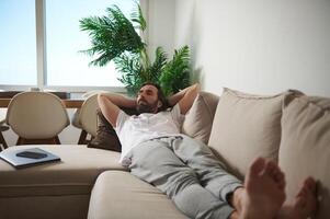 Man Relaxing on a Comfortable Couch in a Cozy Minimalist Living Room Setting photo