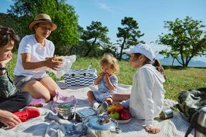 Family Enjoying a Relaxing Picnic in Scenic Mountain Landscape on a Warm, Sunny Day photo