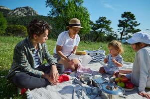 A happy young family Enjoying a Picnic in the Mountains on a Sunny Summer Day photo
