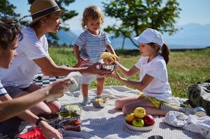 Family Enjoying a Summer Picnic in the Mountains Sharing Tacos on a Sunny Day with Scenic Landscape Views photo