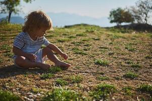 Child Sitting Outdoors in a Field Exploring Nature photo