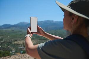 Traveler Exploring Scenic Landscape Using Smartphone with Blank Screen in Vibrant Mountain Setting photo