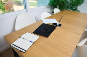 Modern Home Office Workspace with Laptop, Notebook, and Smartphone on Wooden Desk photo