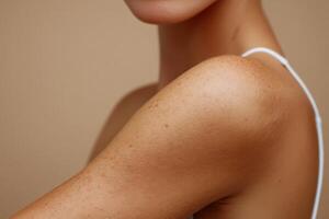 Close-up view of a woman's shoulder and collarbone area against a warm backdrop photo