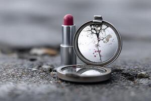 Reflective compact and lipstick on textured stone surface by the waters edge at dusk photo