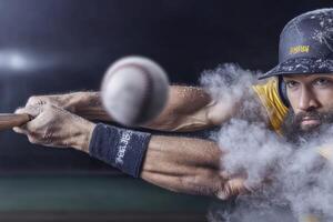 Baseball player swings bat at ball during night game under stadium lights photo