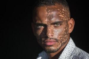 Portrait of a young man with striking eyes and unique facial patterns in natural light photo