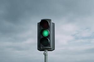 Green traffic light signals vehicles to proceed during overcast weather photo