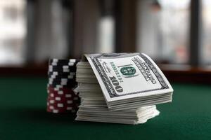 Stacked cash and poker chips on a green felt table in a gaming room photo