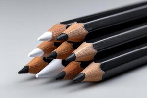 Artistic arrangement of colored pencils in shades of black, white, and brown on a light surface photo