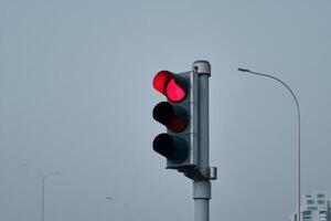 Traffic signal displaying red light at an urban intersection on a cloudy day photo