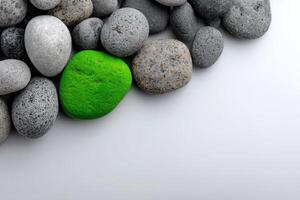 Colorful green stone among various gray pebbles on a light surface photo