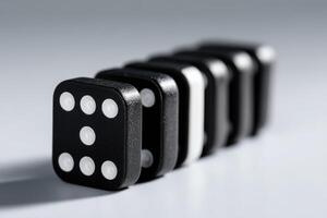 Classic black and white dominoes lined up in a creative arrangement on a white surface photo