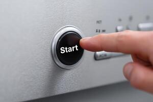 Person pressing start button on modern appliance in a kitchen setting during daytime photo