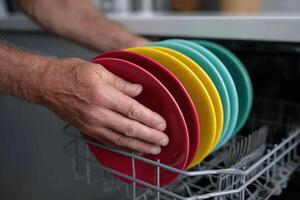 Man organizes colorful plates in a modern dishwasher during a home cleaning session photo