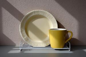 Bright yellow mug and cream plate on a drying rack in natural light photo