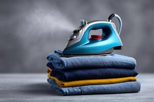 Iron rests on a pile of neatly folded clothes ready for steaming photo