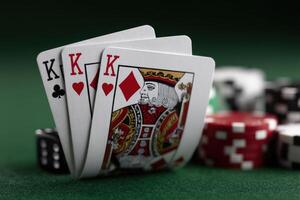 Three kings in a card game on a green felt table with poker chips nearby photo