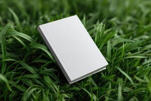 Blank notebook rests on green grass under bright sunlight in a serene outdoor setting photo