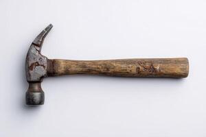 Chipped wooden handle hammer placed on a plain surface in a workshop setting photo