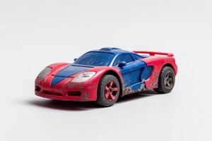 Old toy car with scratches on its surface sitting on a plain background in a vintage style photo