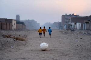 Children play soccer on a dusty street in a Middle Eastern town during sunset photo