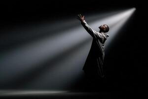 Performer reaches for his shadow under dramatic stage lighting during a captivating moment photo