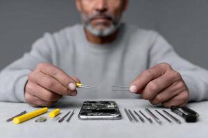 Hands hold miniature tools while repairing a smartphone on a work surface photo