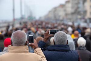 Crowd of urban people using mobile phones at a busy outdoor event in a coastal city setting photo