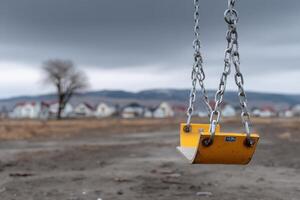 Swing sways gently in empty playground under cloudy skies at dusk photo